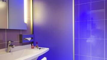 A modern bathroom with a white sink, mirror, and a glass shower enclosure.