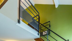 A hotel room with a bed, a wooden staircase, a mirror, and a green wall. - ibis Styles Bourges (Bourges)