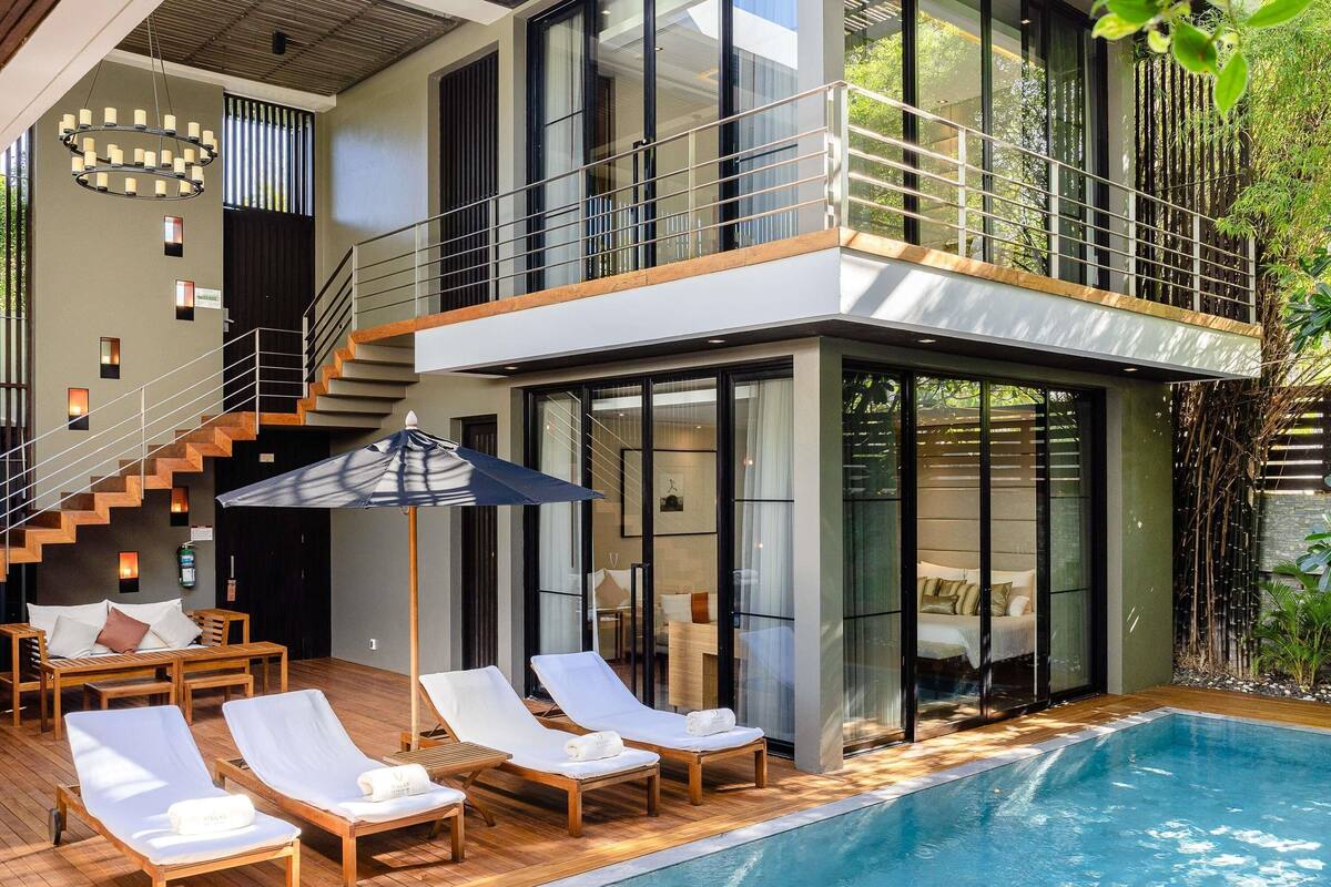 A modern house with a swimming pool, wooden deck, and lounge chairs.