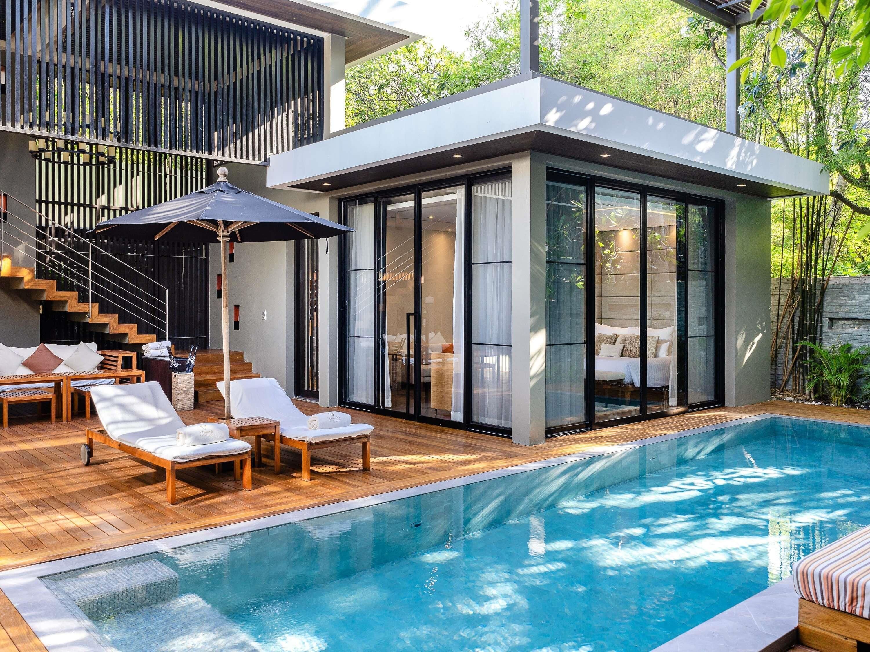 A modern house with a swimming pool, wooden deck, and a glass-enclosed bedroom.