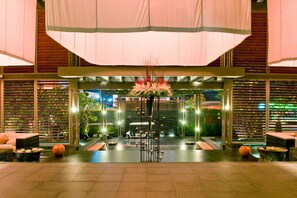 A modern hotel lobby with a central floral arrangement, seating areas, and a view of the street outside. - V Villas Hua Hin - MGallery Collection (Hua Hin)