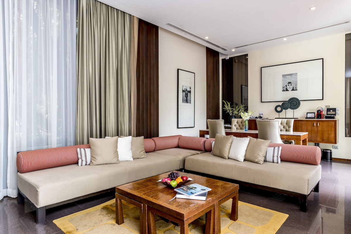 A modern living room with a sectional sofa, a wooden coffee table, and a dining area with a chair and a cabinet.