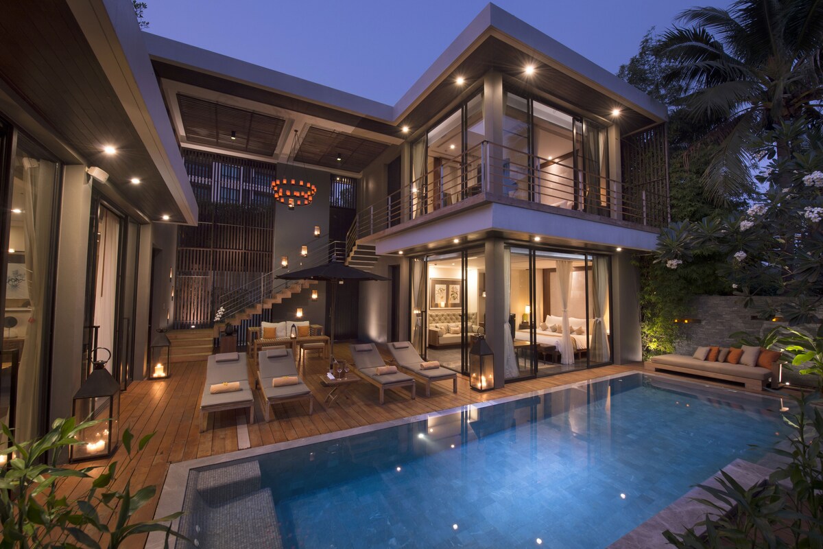A modern two-story house with a swimming pool, outdoor seating, and a staircase leading to the upper level.