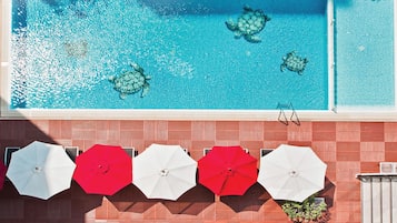 A swimming pool with clear blue water and sea turtles, surrounded by a red and white tiled deck.