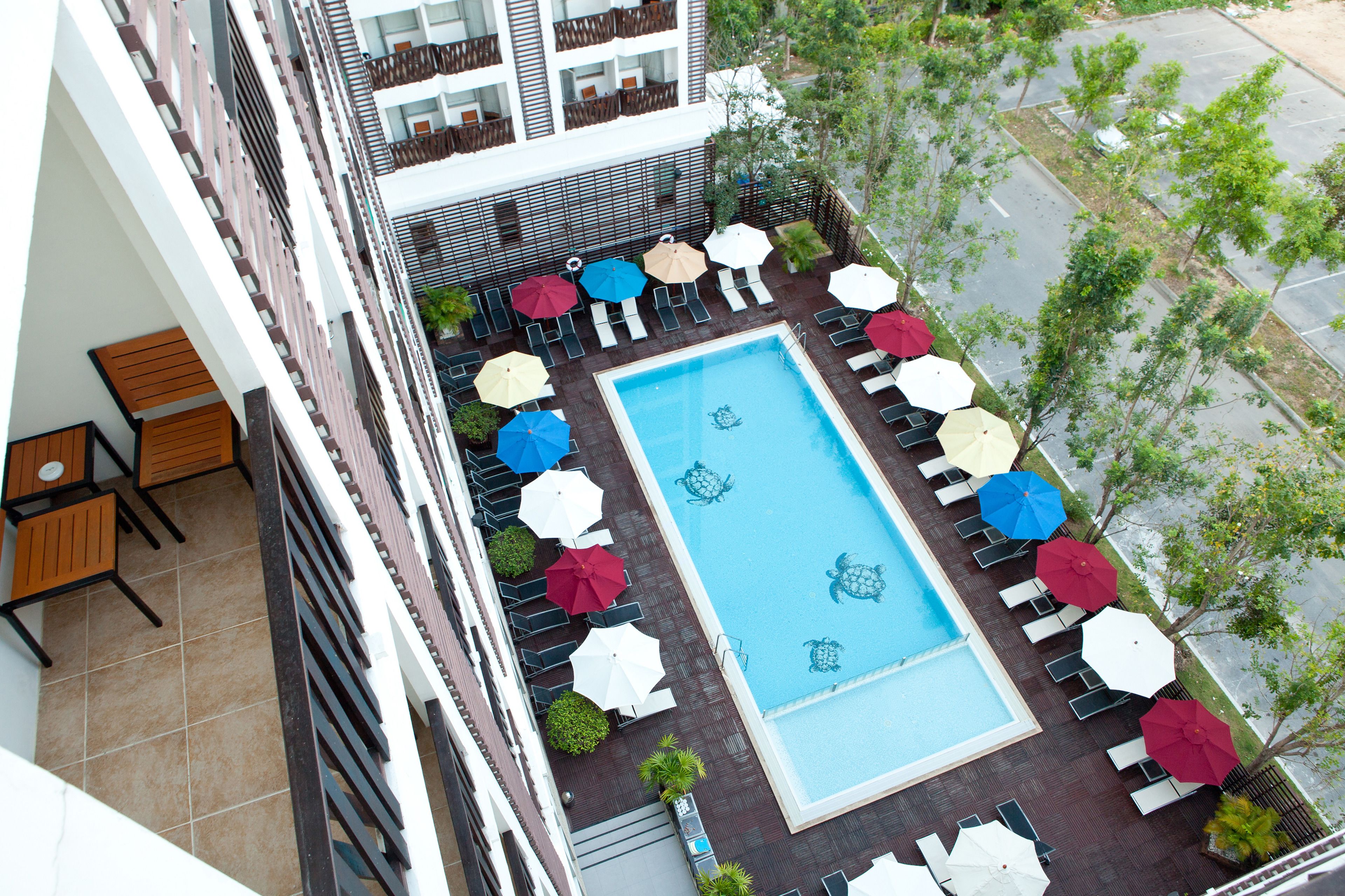 A rooftop pool area with multiple umbrellas, lounge chairs, and a clear view of the surrounding buildings.