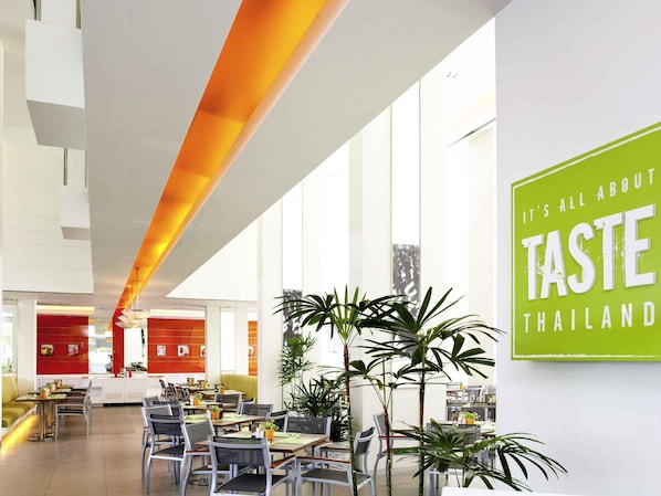 A modern restaurant interior with high ceilings, large windows, and a prominent green sign. - ibis Pattaya (Pattaya)