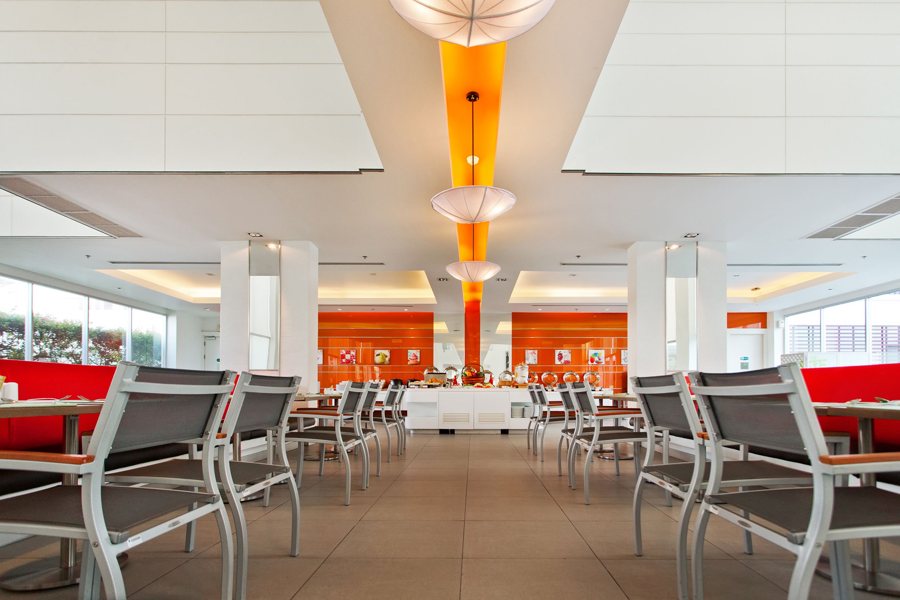 A spacious dining area with high ceilings, modern chairs, and a central serving station.