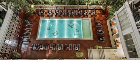 Una piscina en la azotea con varias zonas de estar y vistas de la vegetación circundante.