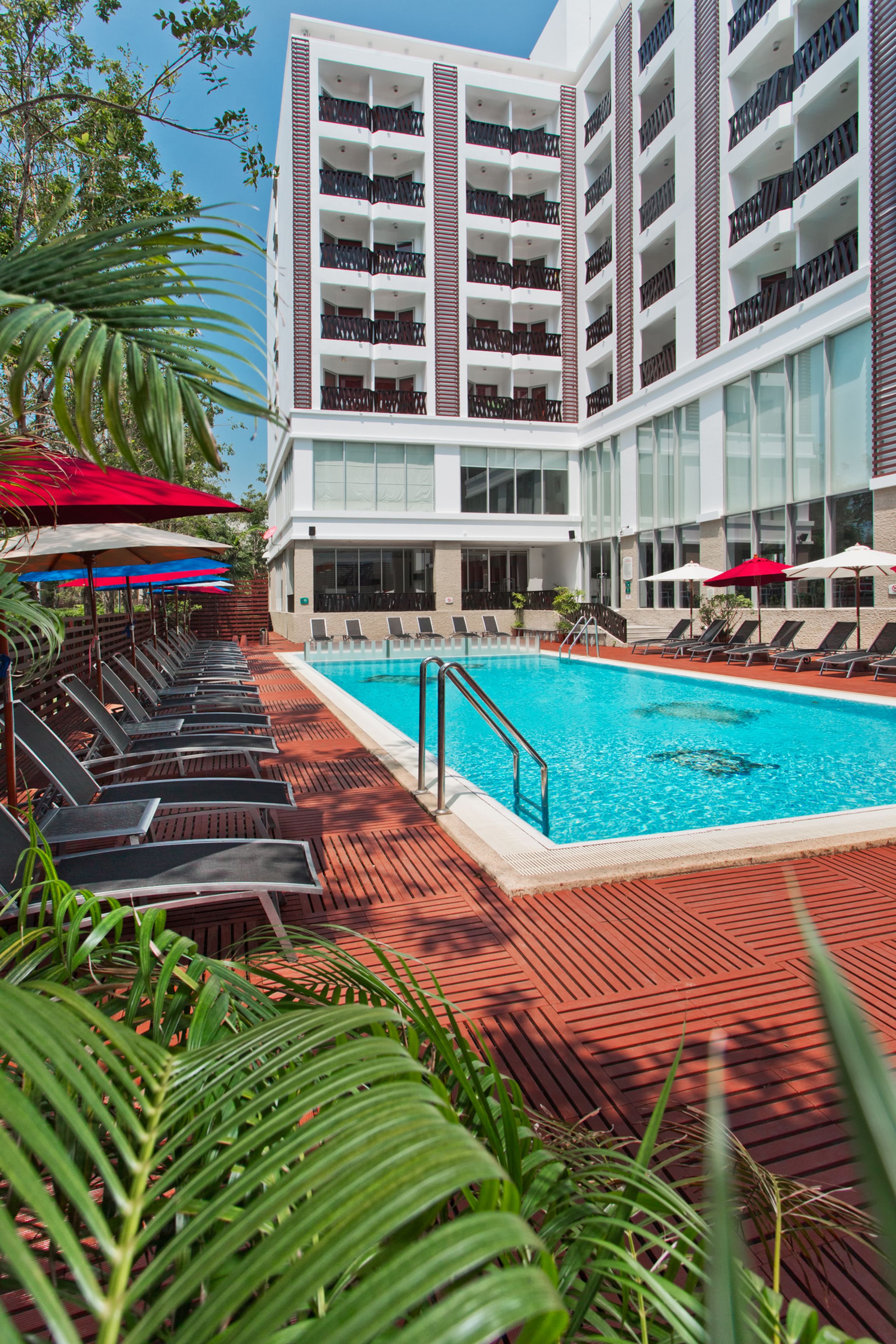 Un hotel con piscina, tumbonas y sombrillas.