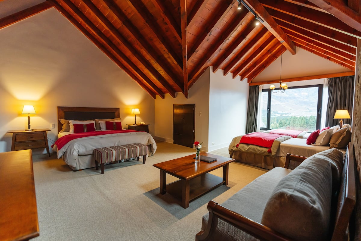 Ein Hotelzimmer mit Holzboden, zwei Betten, einer Couch, einem Couchtisch und Lampen.