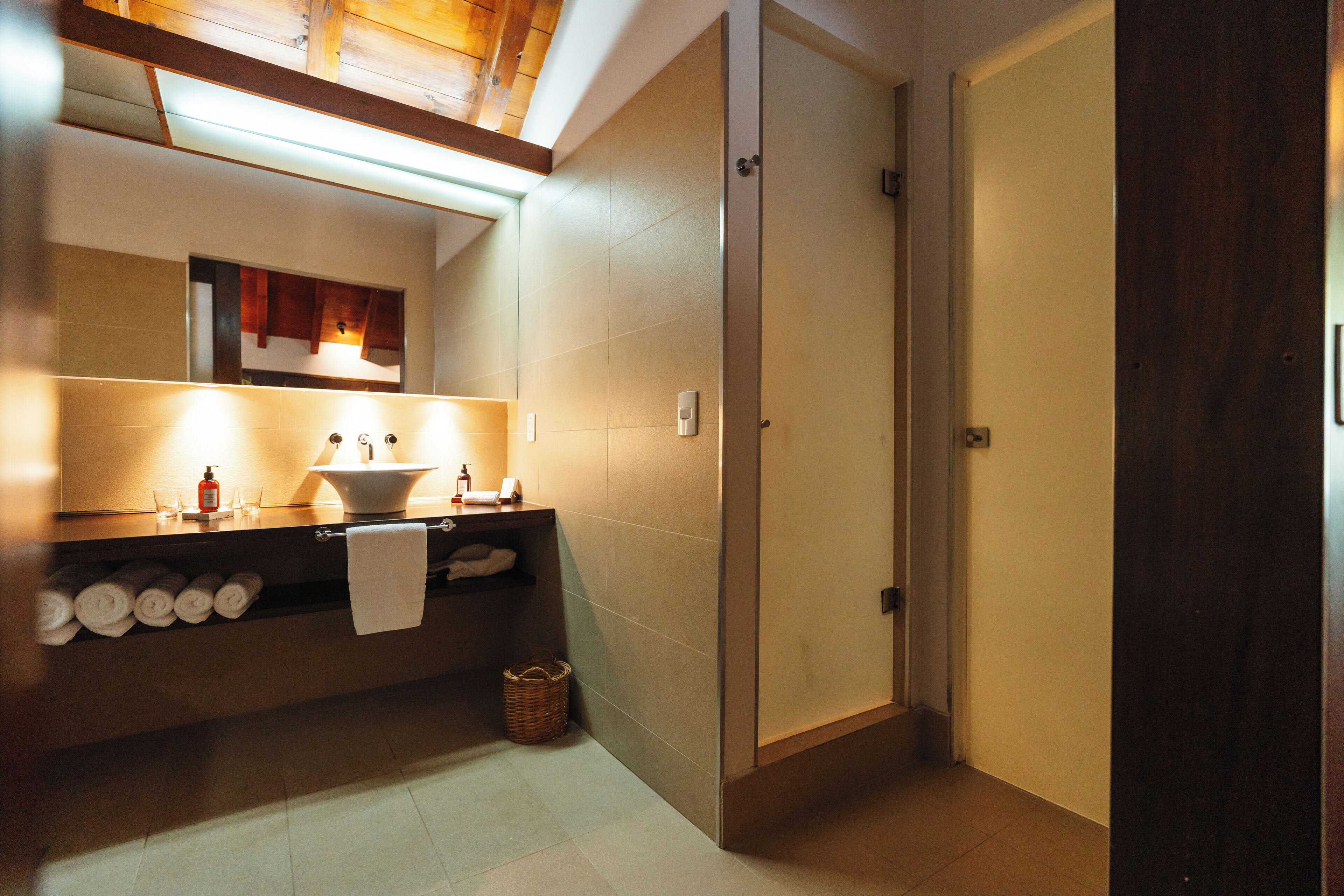 A modern bathroom with a large mirror, a sink with a towel rack, and a shower area.