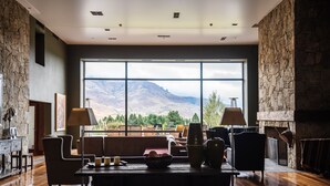 Ein geräumiges Wohnzimmer mit großem Fenster und Bergblick, Holzboden und modernen Möbeln.