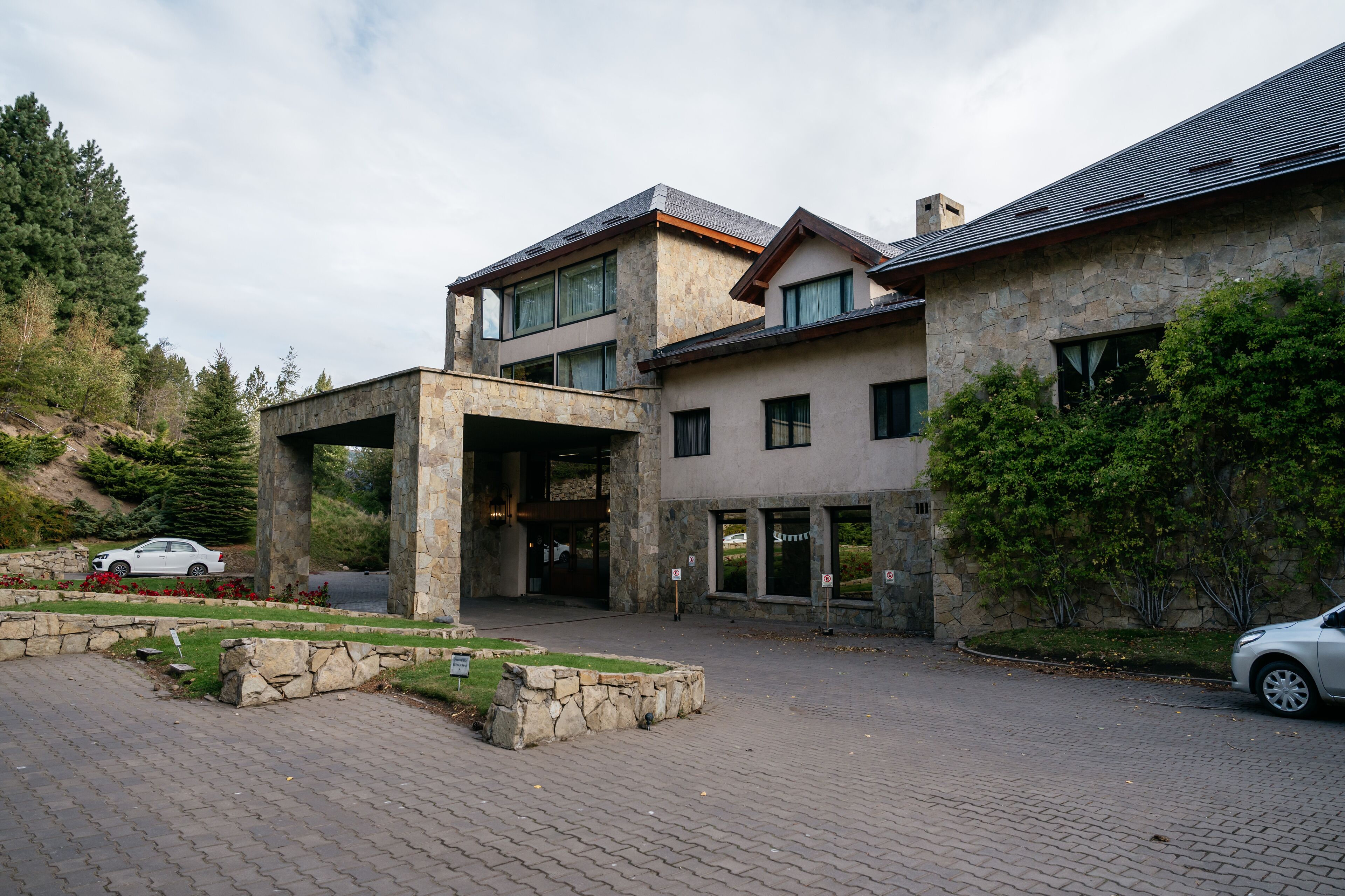 A modern two-story building with a stone facade, large windows, and a covered entrance.