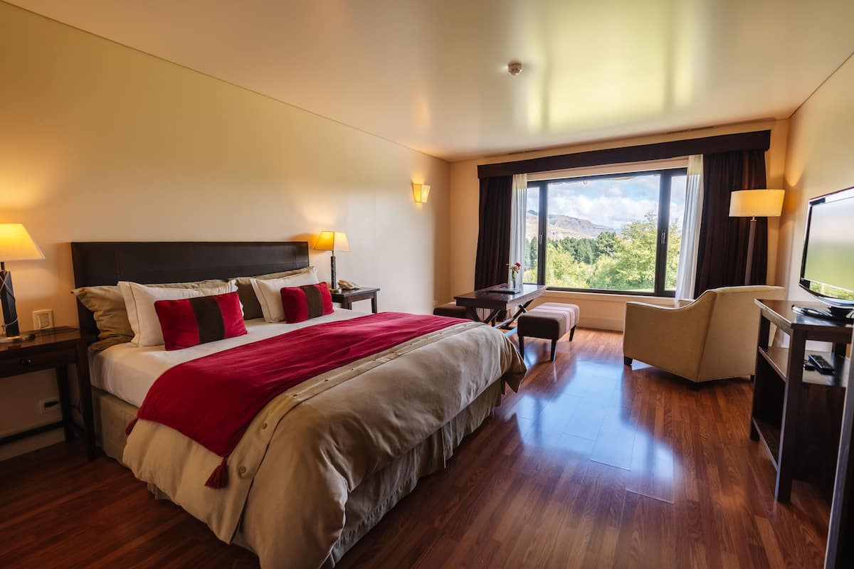Ein Hotelzimmer mit einem großen Bett, einem Schreibtisch, einem Sessel und einem Fernseher.
