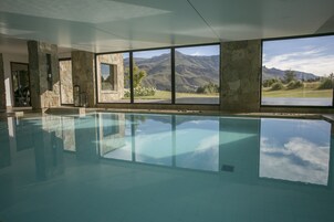 Una piscina techada, una piscina al aire libre, sombrillas