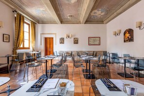 A spacious dining area with clear glass chairs and tables, a wooden door, and wall-mounted artwork.