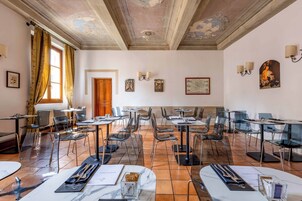 A spacious dining area with clear glass chairs and tables, a wooden door, and wall-mounted artwork.