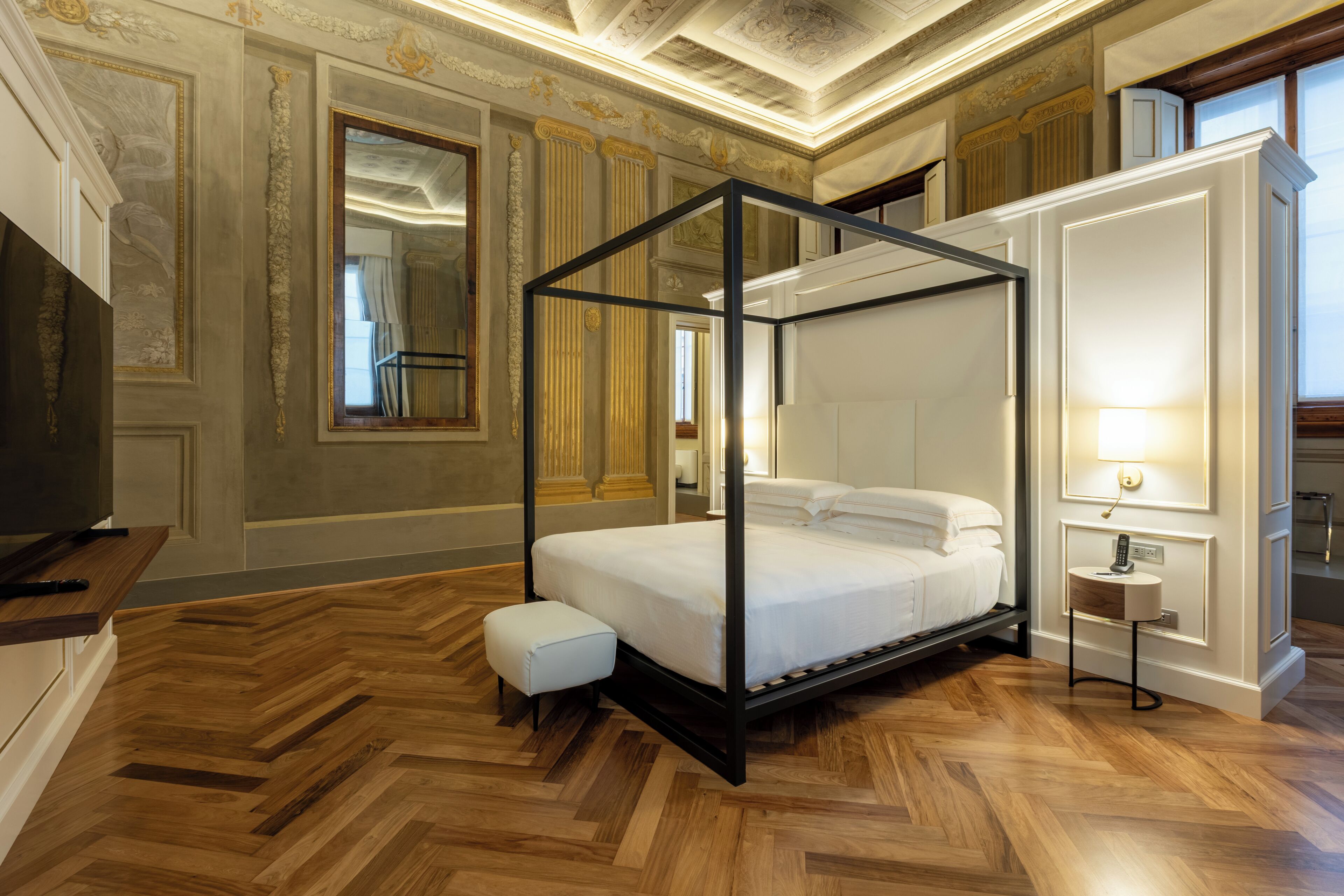 A four-poster bed with a wooden floor and ornate wall decorations.