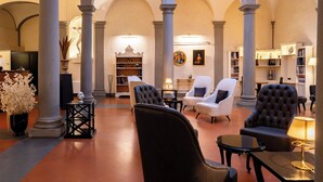 Eine großzügige Lobby mit hohen Decken, Säulen und einer zentralen Sitzgruppe mit Stühlen und Tischen.