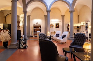 Un hall d’entrée spacieux, doté de hauts plafonds, de colonnes et d’un espace de détente central avec des chaises et des tables.
