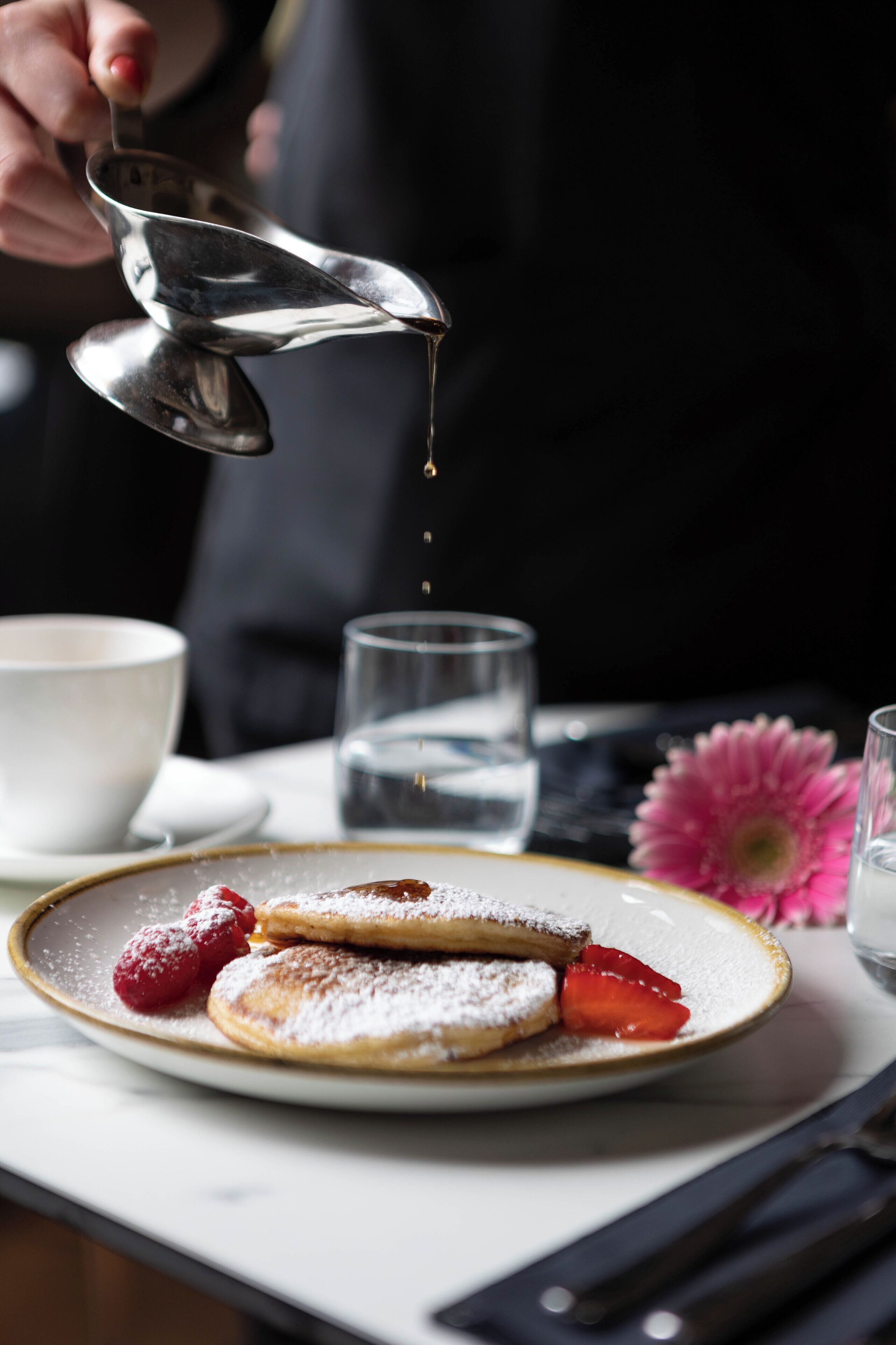 Un piatto con pancake, fragole e zucchero a velo.