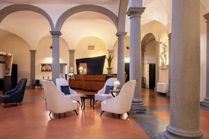 A spacious lobby with high ceilings, arched columns, and a reception desk.