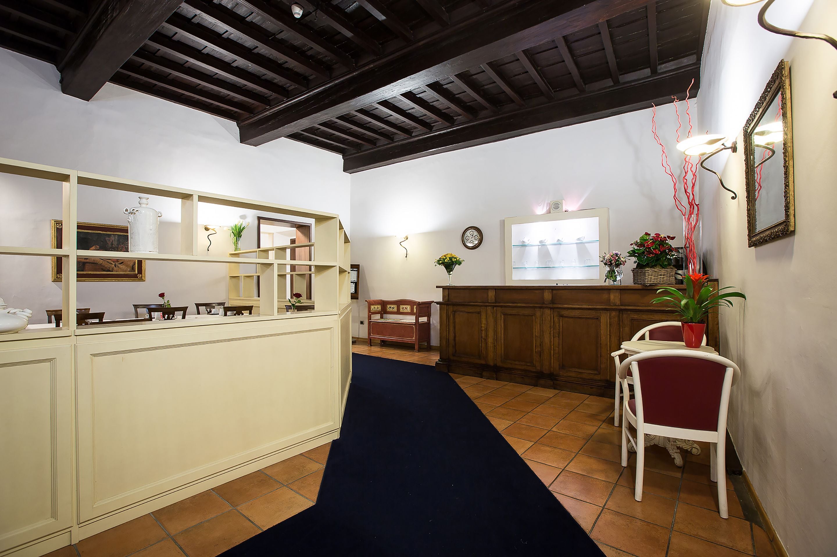 A reception area with a counter, chairs, a potted plant, and a mirror.