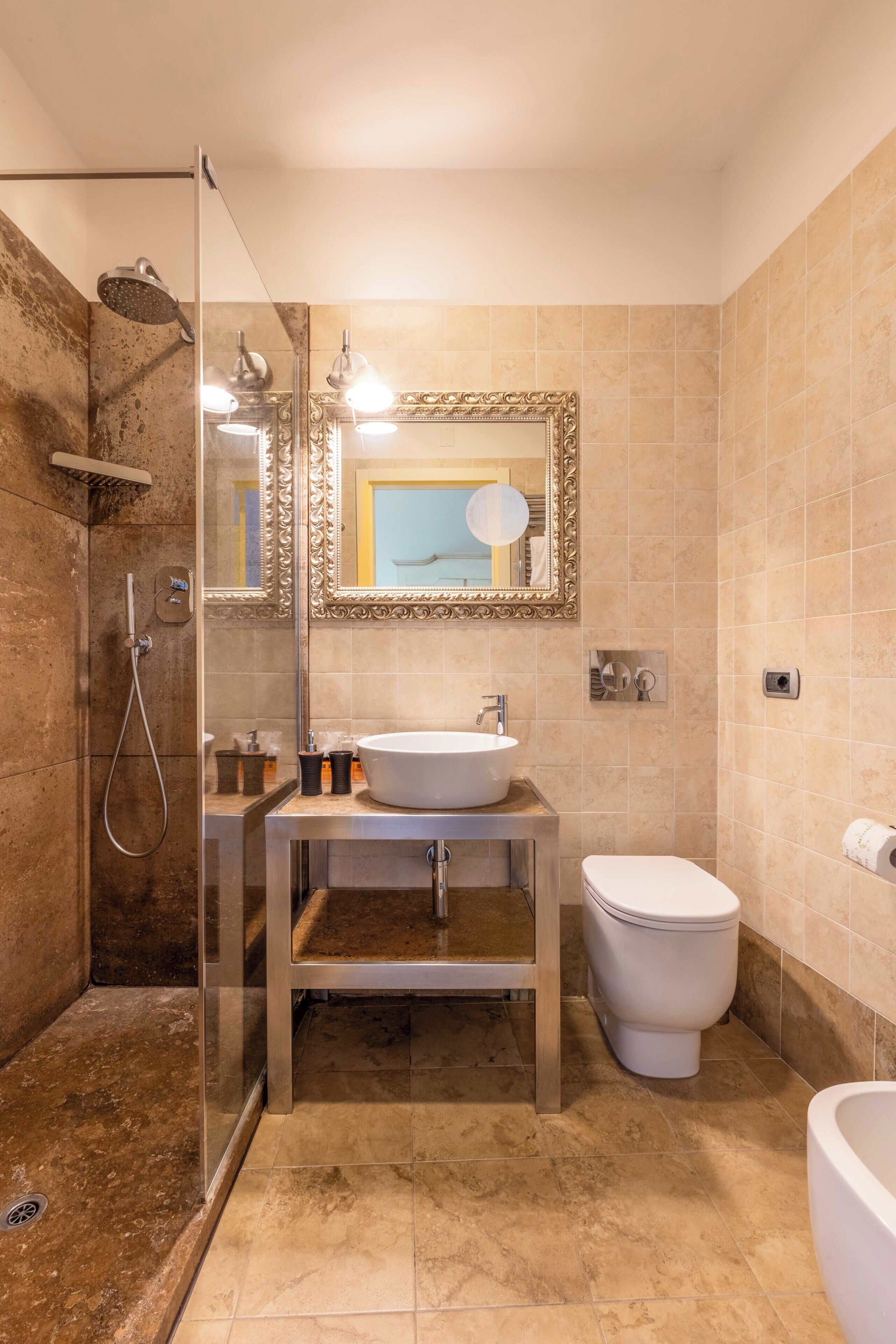 A bathroom with a glass-enclosed shower, a sink with a mirror, and a toilet.