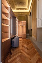 Un interior moderno con estanterías de madera, una zona de estar y una escalera que lleva a una puerta.