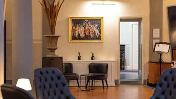 Una hall con due poltrone, un quadro di grandi dimensioni e una reception.