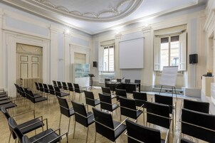A conference room with rows of black chairs, a whiteboard, and a piano.