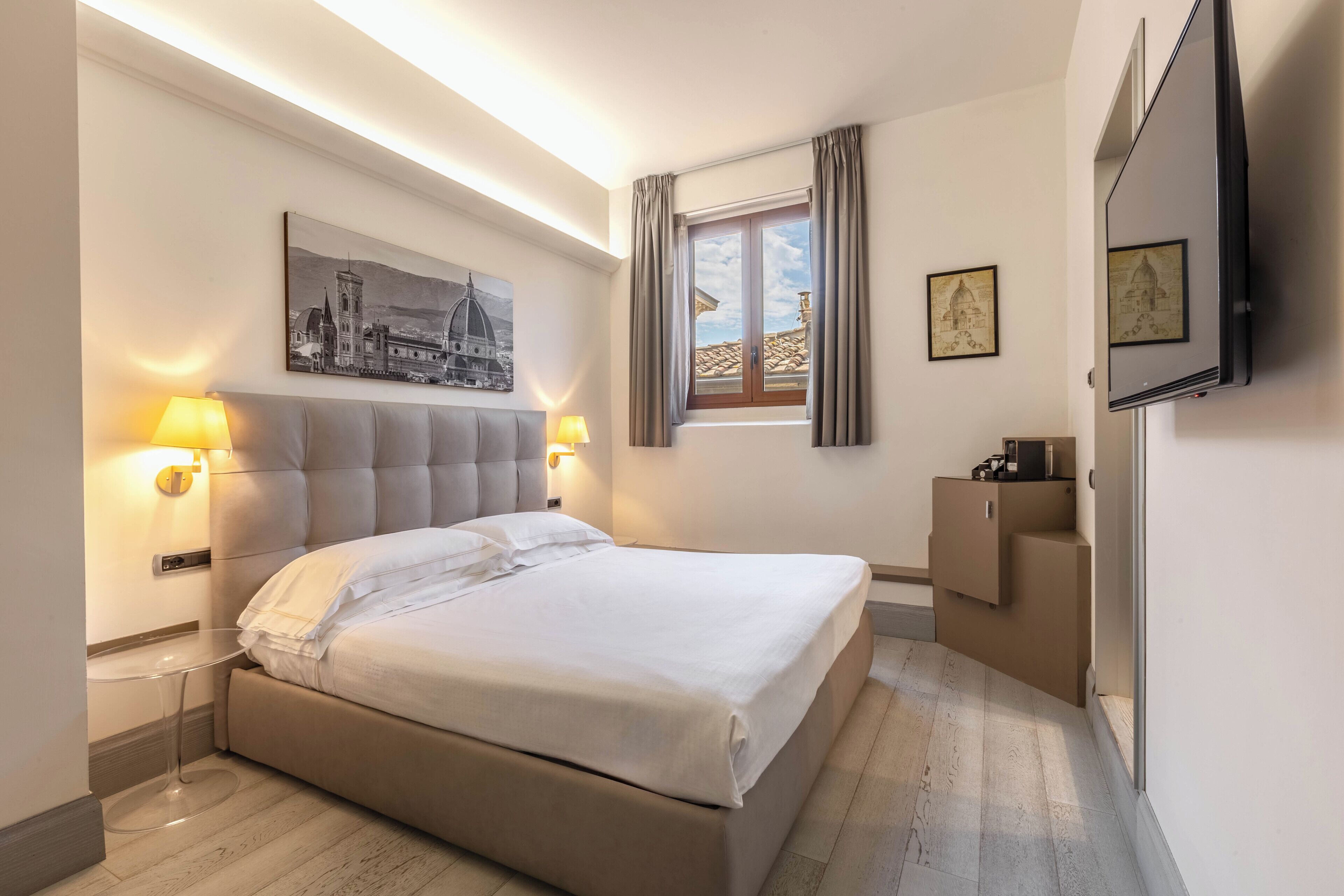 Una camera da letto moderna con un letto grande, lampade sui comodini, una TV a schermo piatto e opere d'arte alle pareti.