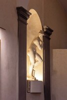 A classical statue in a niche with a book titled "The Story of the Painter" placed below it.