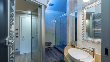 Un bagno moderno con doccia in vetro, una parete in marmo e uno specchio grande con cornice elaborata.