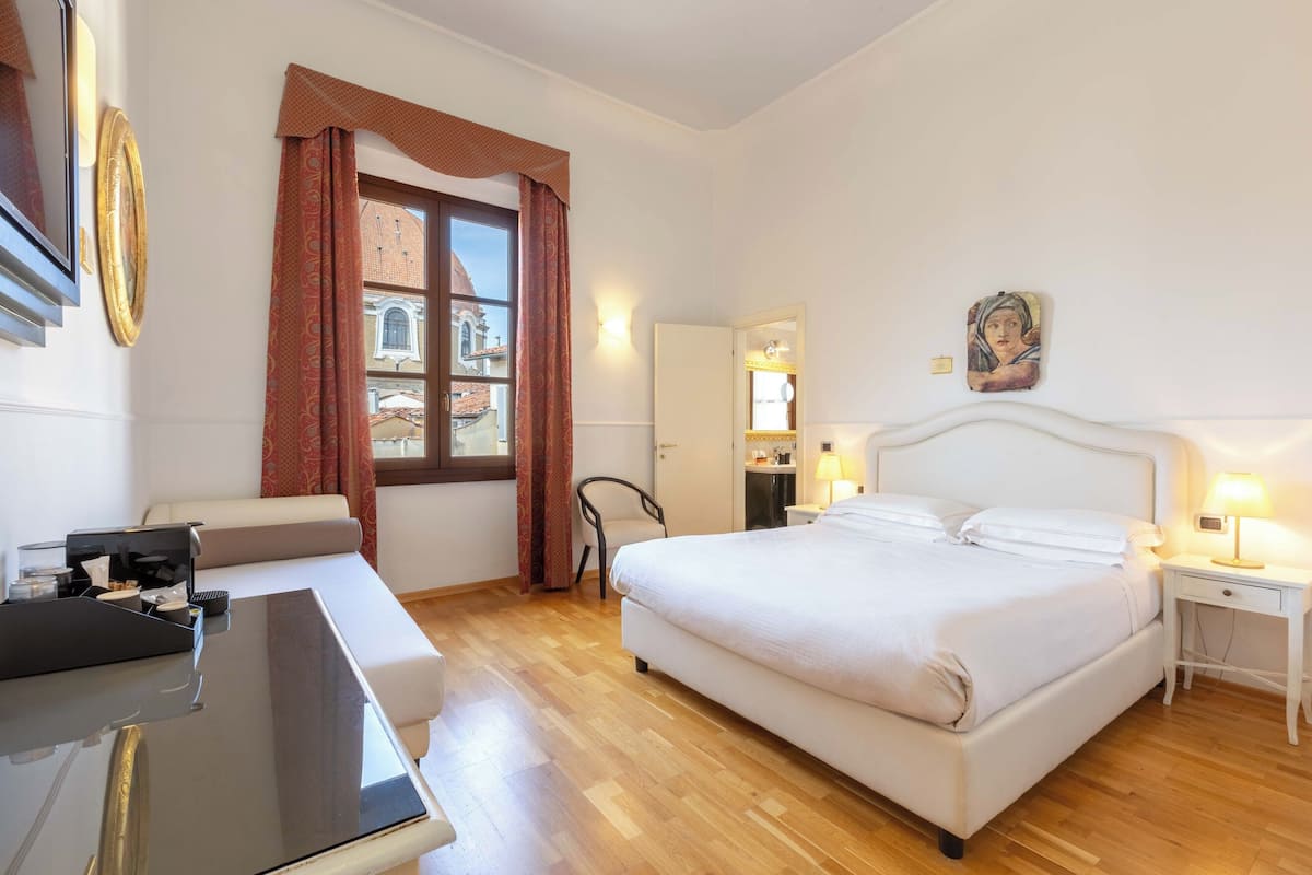 Een hotelkamer met een bed, nachtkastjes, een bureau en een stoel.