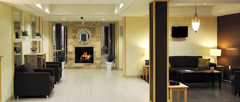 Un vestíbulo de hotel con chimenea, zona de estar y televisor.