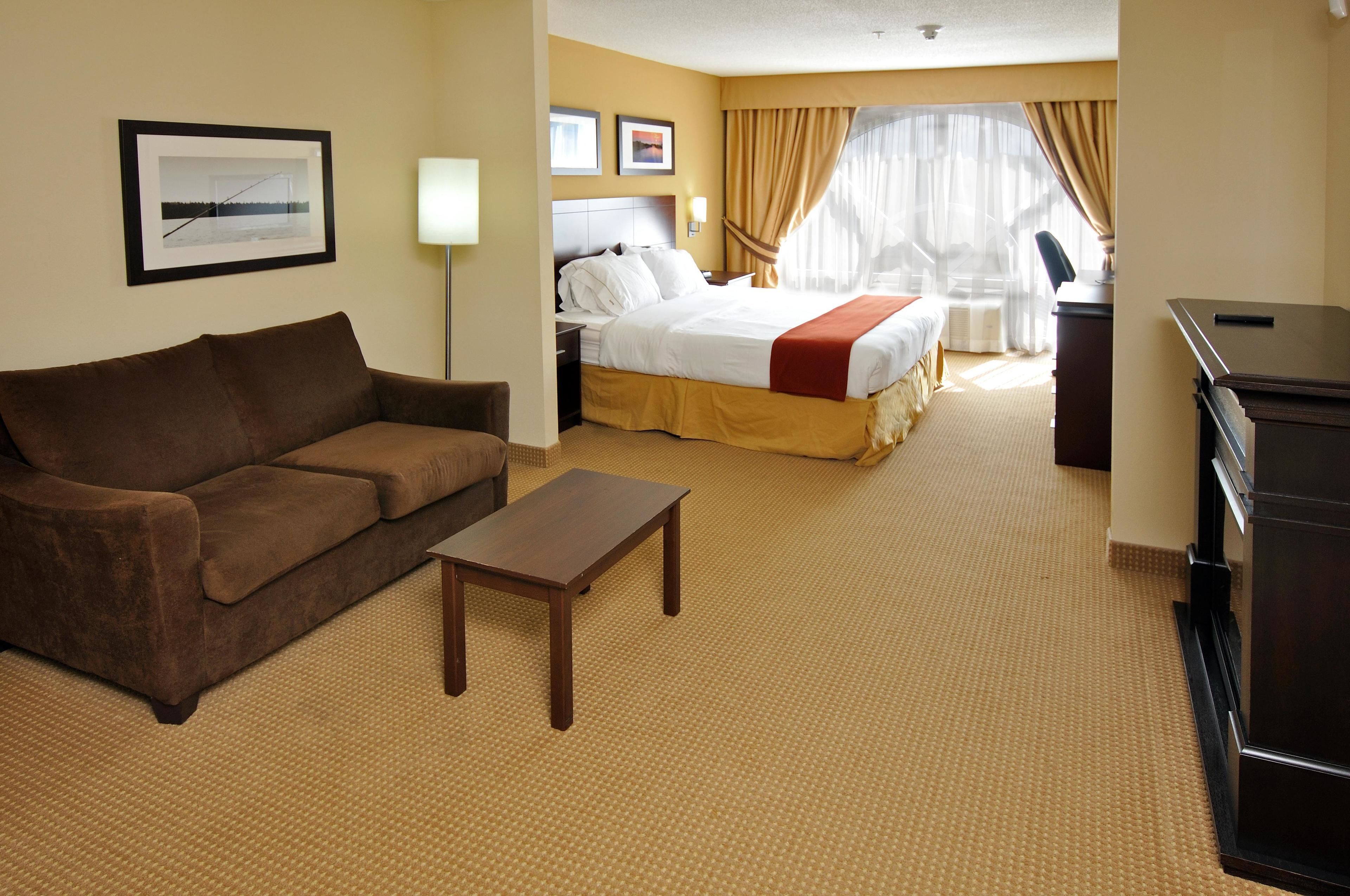 A hotel room with a bed, a sofa, a small table, and a desk.