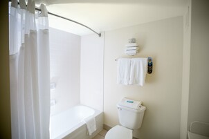 Un baño con bañera, inodoro y toallero con toallas.