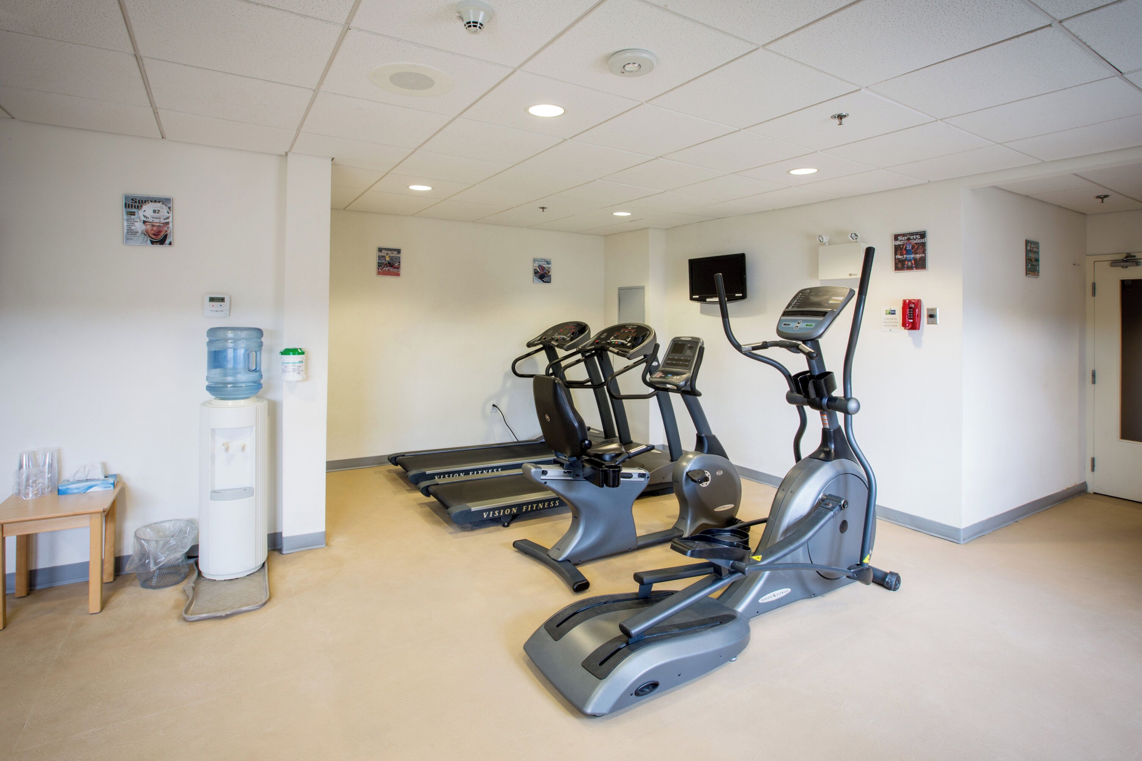 Un centre de remise en forme équipé de tapis de course, d’un appareil elliptique et d’un distributeur d’eau.