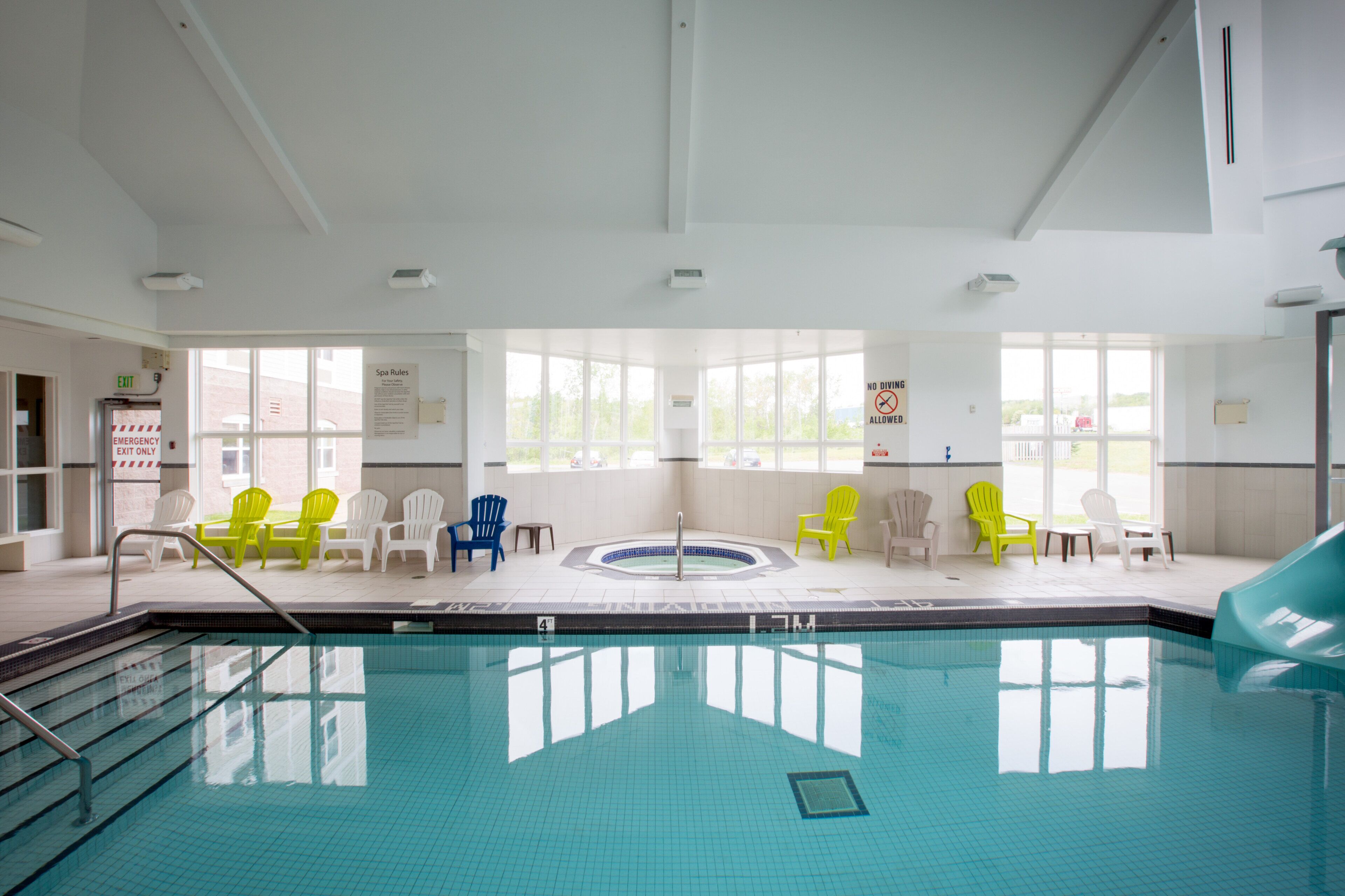 A swimming pool with a hot tub, surrounded by chairs, and a sign indicating no diving is allowed.