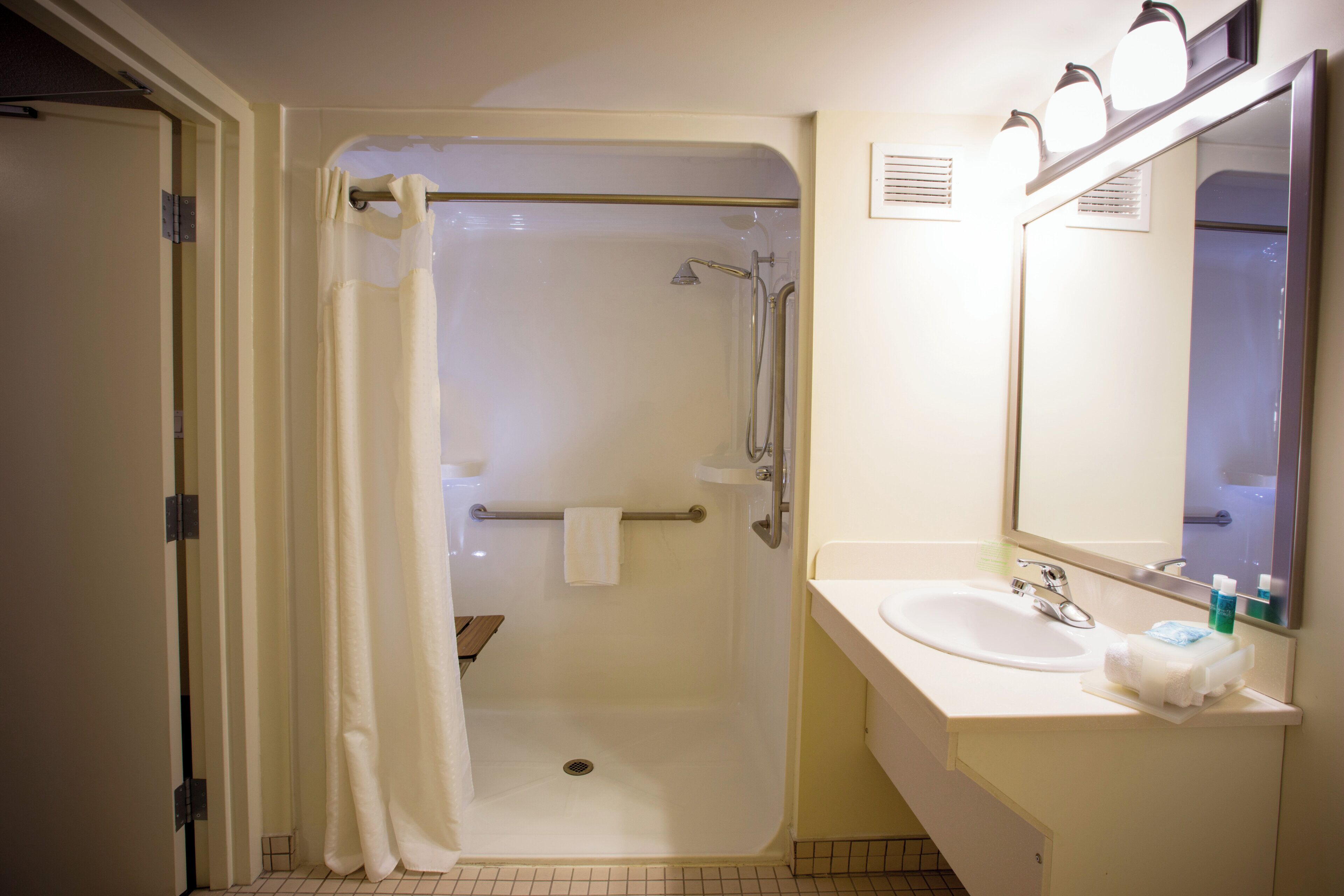 A bathroom with a shower, a sink, and a mirror.