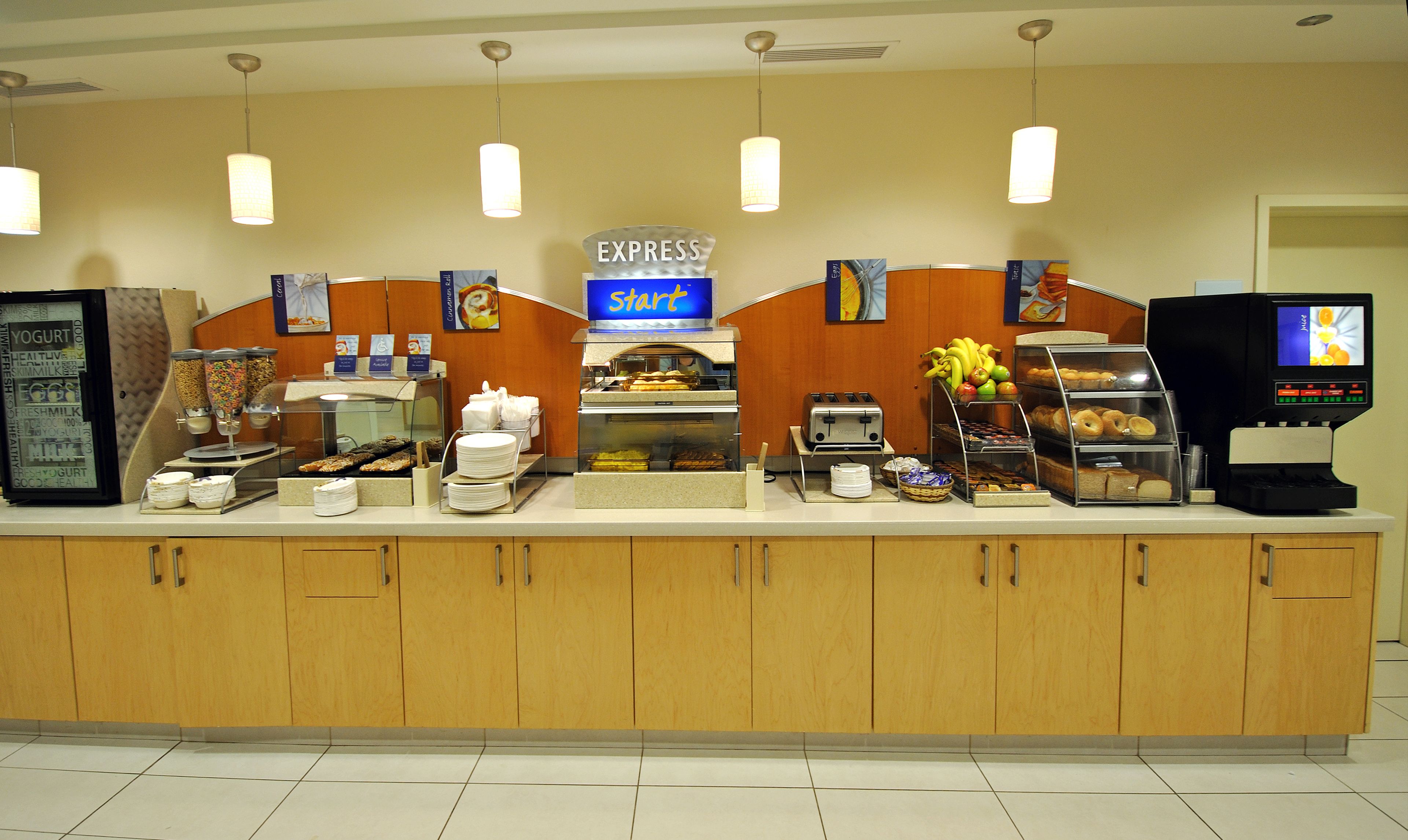 A buffet counter with various food items, a coffee machine, and a juice dispenser.