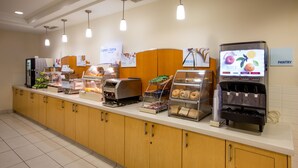 Una barra de desayuno con diversas opciones de comida y un dispensador de zumo.