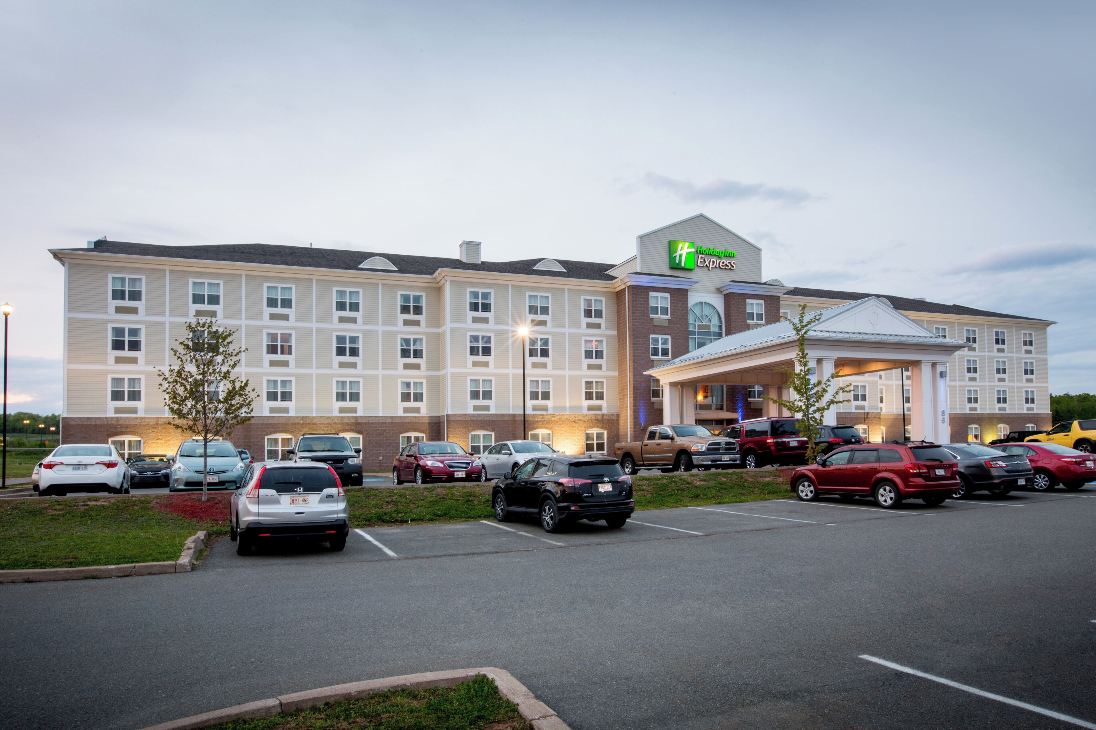 A Holiday Inn Express hotel with multiple parking spaces and a variety of vehicles parked in front.