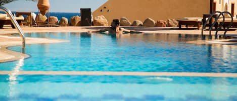 Una piscina al aire libre, sombrillas, tumbonas