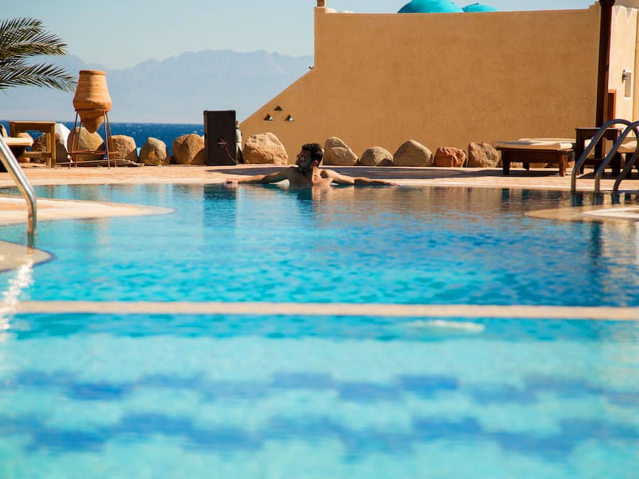 Una piscina al aire libre, sombrillas, sillones reclinables de piscina
