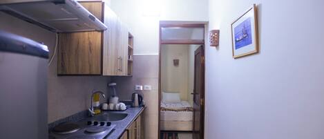 A compact kitchen with a stove, sink, and wooden cabinets.