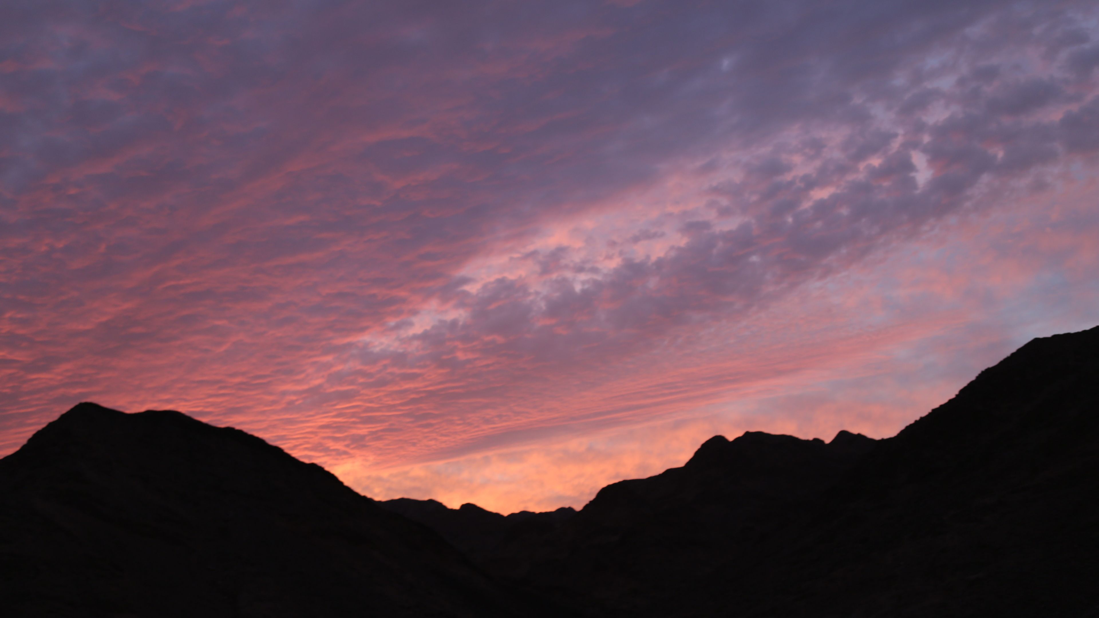 A mountainous landscape with a sunset sky.