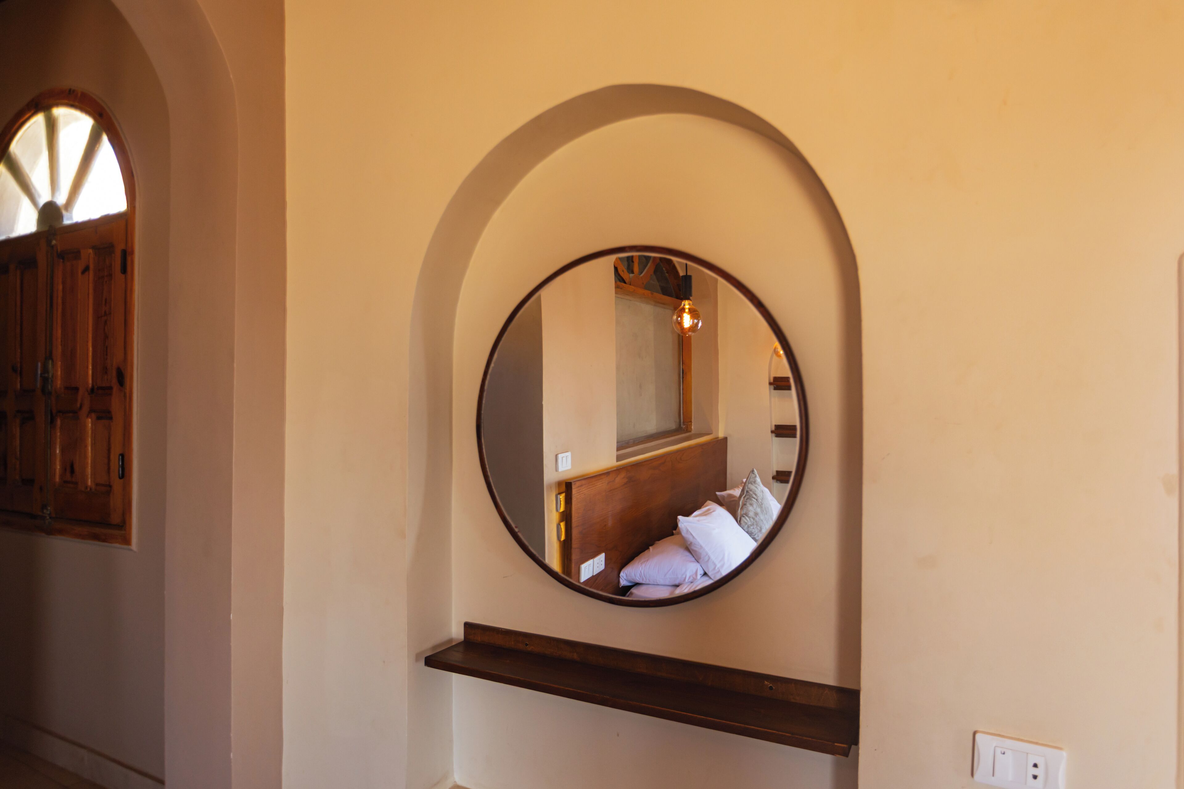 A round mirror with a wooden frame mounted on a wall.