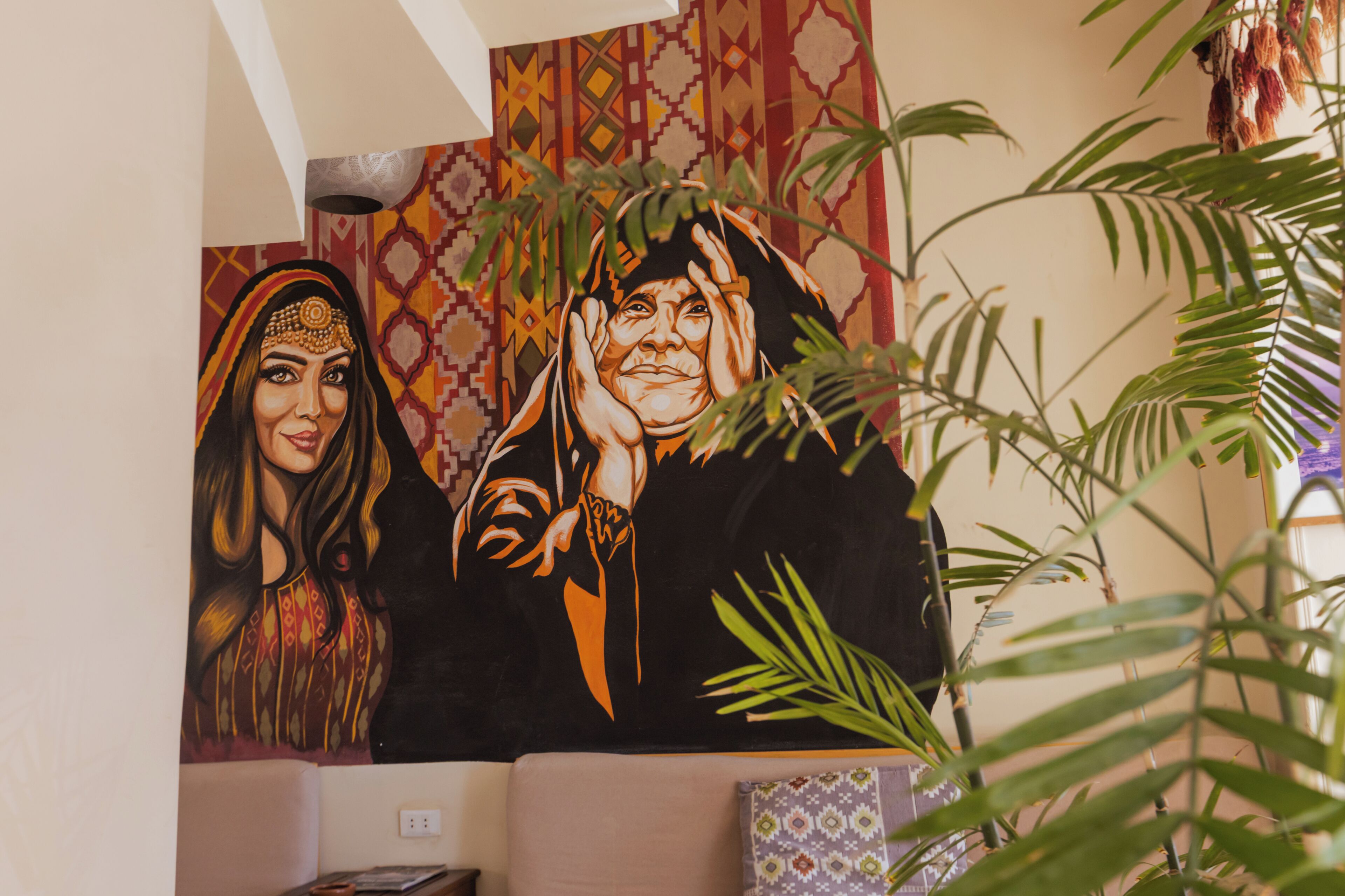 Quarto com um grande mural na parede, um sofá e um vaso de planta.